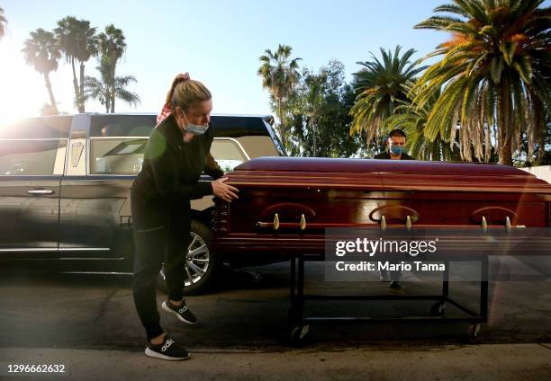 Embalmer and funeral director Kristy Oliver and funeral attendant Sam Deras prepare to load the casket of a person who died after contracting...