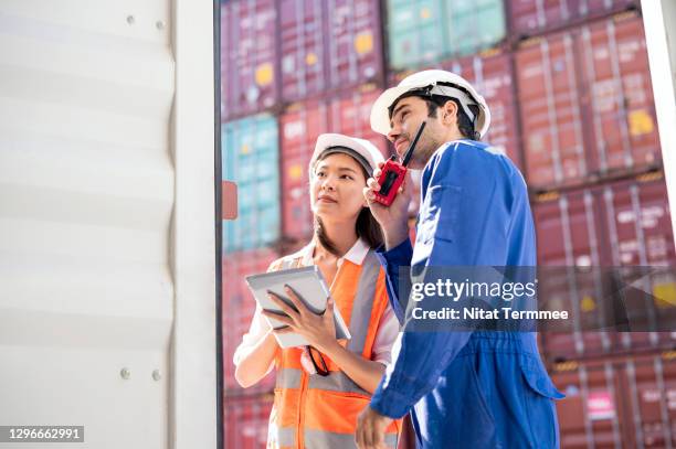 female shipping broker and male dock controller in front of cargo container while negotiate operating freight rate.  freight forwarder business concept. - cb funk stock-fotos und bilder