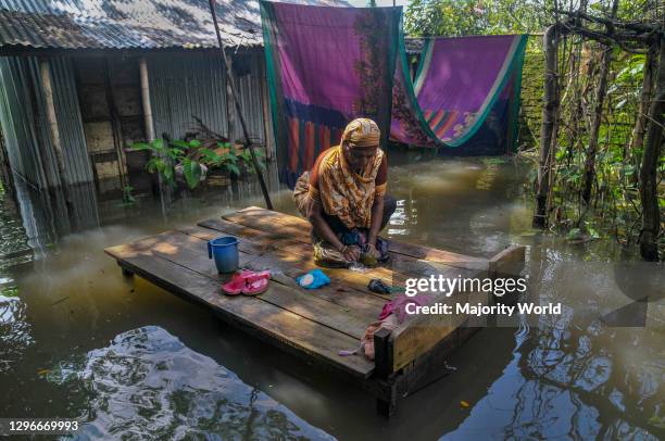 Due to heavy rains the river is overflowing. A woman sitting on a bed washing cloths in the border district town of Sunamganj, Sylhet, Bangladesh.