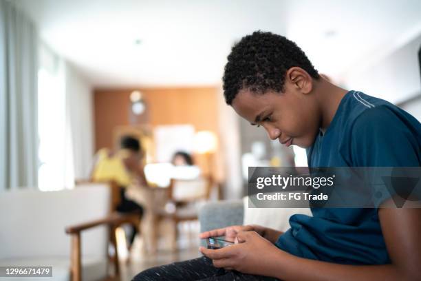 de jongen van de tiener die smartphone thuis gebruikt - verkeerde houding stockfoto's en -beelden