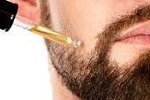 Male face and pipette with a oil for a beard growth
