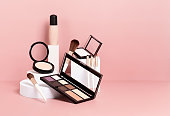 Make up products prsented on white podiums on pink pastel background.