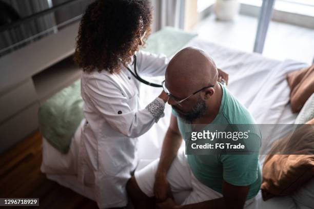 doctor listening to patient's heartbeat during home visit - human heart stock pictures, royalty-free photos & images