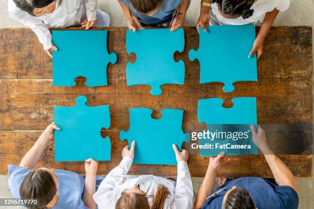 ouvriers de soins de santé retenant de grandes pièces de puzzle ensemble - big puzzle photos et images de collection