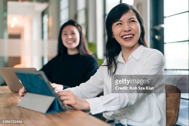 glückliche asiatische frau mittleren alters, die an einem umschulungskurs teilnimmt - successful asian team stock-fotos und bilder