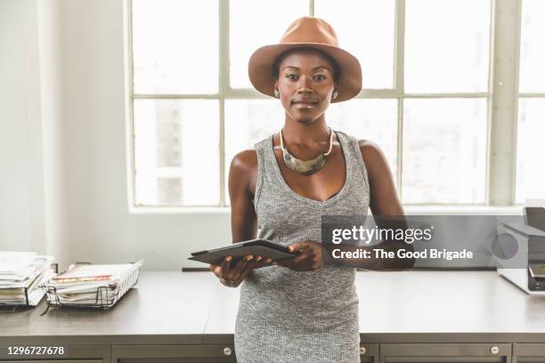 portrait of confident female professional wearing hat holding digital tablet - fashion in an age of technology costume institute gala after parties stockfoto's en -beelden