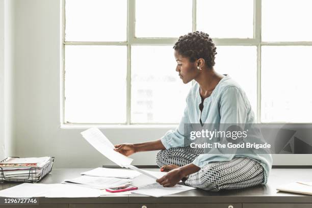 businesswoman sitting on desk at creative office - african american ethnicity stock pictures, royalty-free photos & images