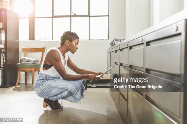 businesswoman looking at documents in filing cabinet at office - filing documents stock pictures, royalty-free photos & images