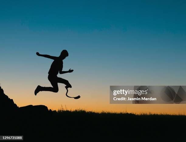 running amputee with prosthetic leg at sunset - sportler mit behinderung stock-fotos und bilder