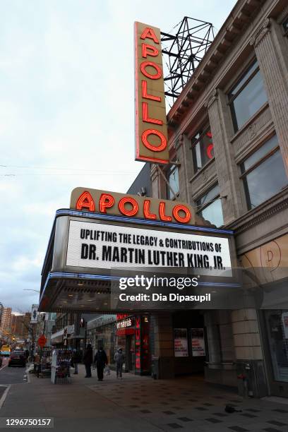 People wearing protective masks walk under a marquee that reads "Uplifting the legacy & contributions of Dr. Martin Luther King, Jr. At the Apollo...