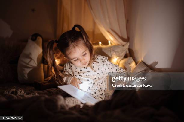 beautiful little girl reading book lying on the bed - menina fantasia bonita imagens e fotografias de stock