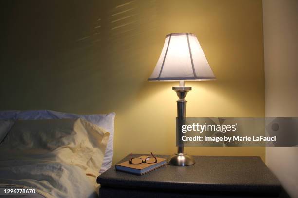 bedroom night table with lamp, book and reading glasses - tavolino di servizio foto e immagini stock