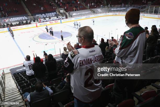 Limited attendance fans, stand and cheer after the notional anthem to NHL game between the Arizona Coyotes and the San Jose Sharks at Gila River...