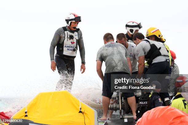 American Magic skipper Dean Barker watches as water is pumped from the boat as the crew try to stop it sinking after capsizing in race two against...