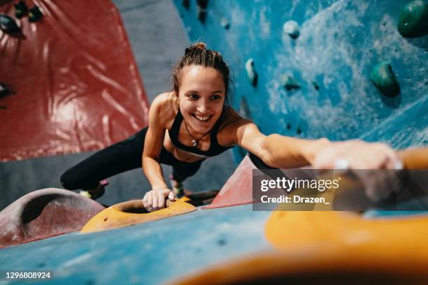 visão de ângulo alto de mulher magra e forte subindo na parede de pedregulho - bouldering - fotografias e filmes do acervo