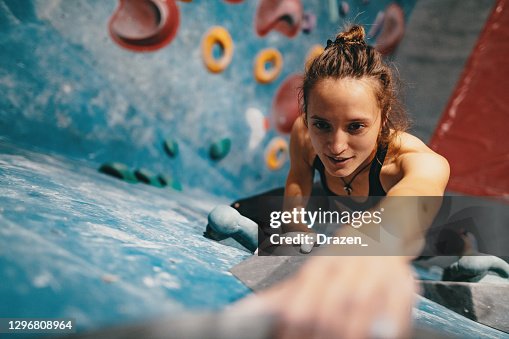 Vista ad alto angolo della donna magra forte che si arrampica sulla parete del masso Vista ad alto angolo della donna magra forte che si arrampica sulla parete del masso