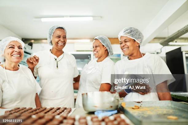 grupo de confiterías que trabajan riendo juntos en una fábrica de chocolate - fábrica-de-chocolate fotografías e imágenes de stock