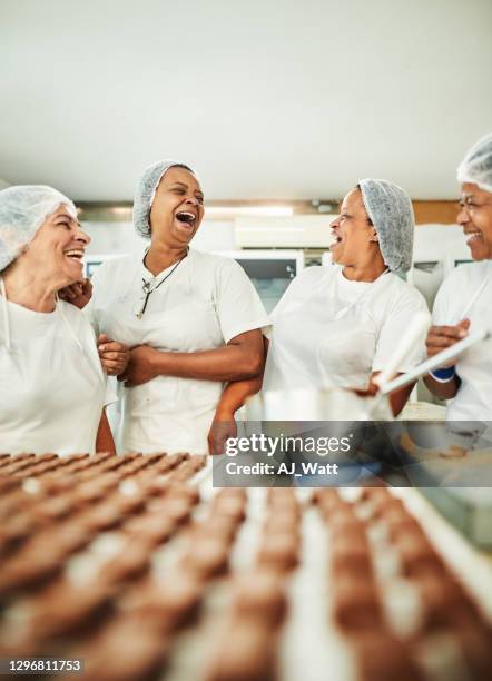 grupo risueño de confiterías trabajando juntos en una fábrica de chocolate - fábrica de chocolate fotografías e imágenes de stock