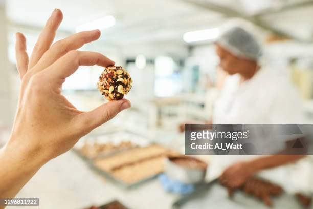 schokoladenfabrikarbeiterin hält eine konditorei in der hand - qualitätsprüfer stock-fotos und bilder