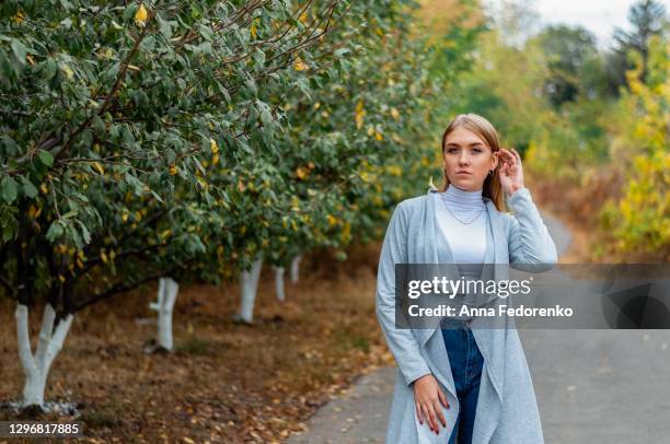 portrait of a blonde girl against the background of an alley with trees - 髪に手をやる　女性 ストックフォトと画像