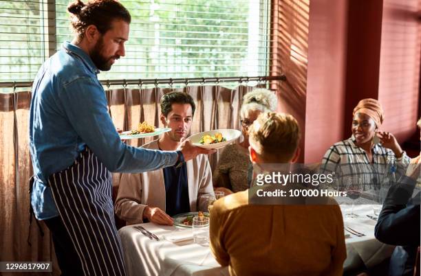 waiter serving plates of food to customers in restaurant - brasserie fotografías e imágenes de stock