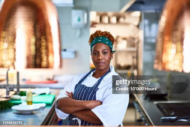 female chef in commercial kitchen with arms folded - kochlehrling stock-fotos und bilder