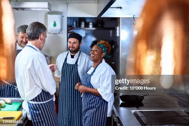 four chefs chatting in commercial kitchen - woman uniform stock pictures, royalty-free photos & images