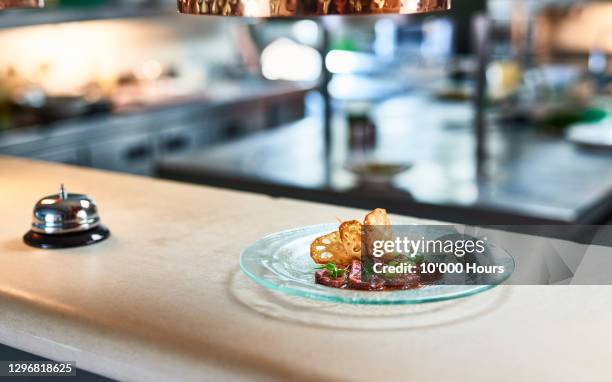 glass plate with meal on service counter with bell - finishing food stock pictures, royalty-free photos & images