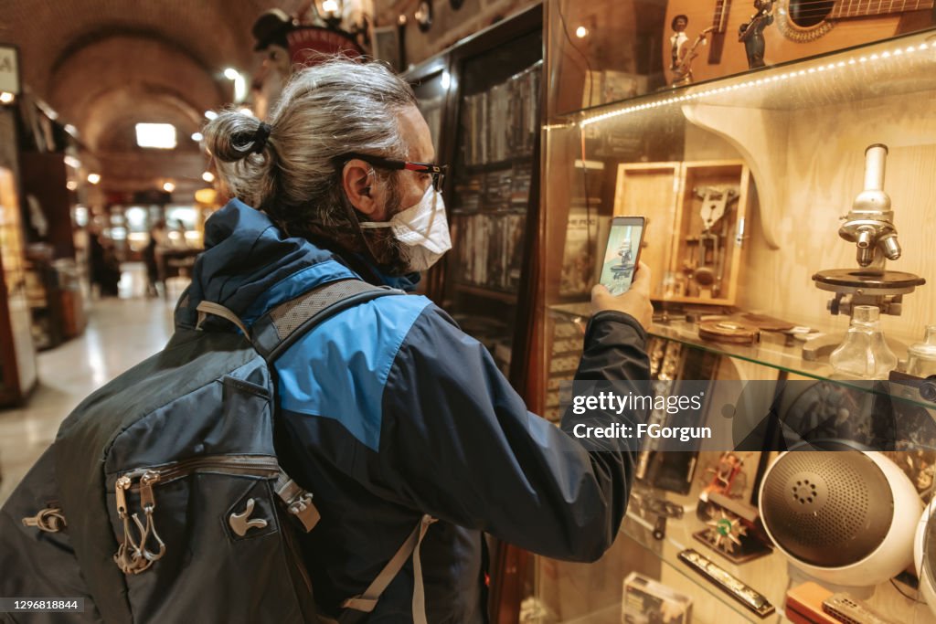 Tourist taking a photo of old microscope in antique shop