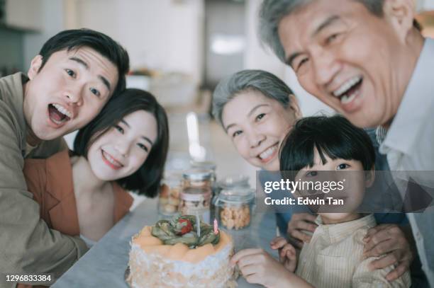 asian chinese grandfather celebrating grandson birthday holding smart phone taking selfie photographing his family at living room - asian senior couple stock pictures, royalty-free photos & images