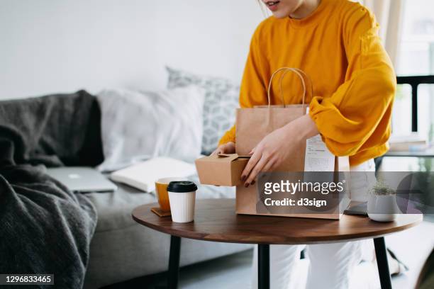 cropped shot of young asian woman holding boxes of home delivery takeaway food that have just arrived to share, serving on the coffee table. eating at home concept - food delivery fotografías e imágenes de stock