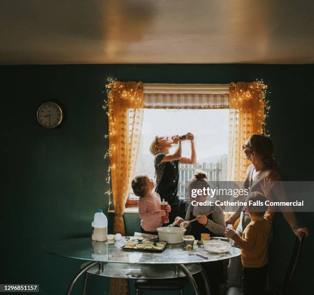 children baking at a table with mum supervising - girl squeezes whipped cream directly into her mouth - wire whisk stock pictures, royalty-free photos & images