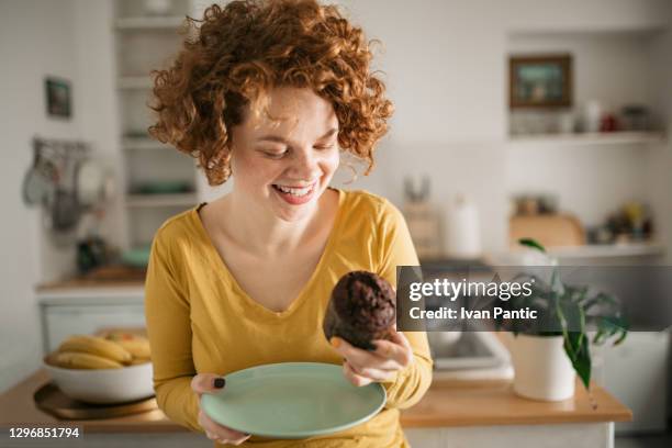 felice giovane donna caucasica che sta facendo una colazione leggera a casa - brownie foto e immagini stock