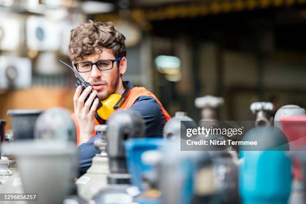 male worker working in a gas cylinders distribution warehouse while talking on walkies talkie negotiate delivery schedule with coworker. - sprengkörper stock-fotos und bilder