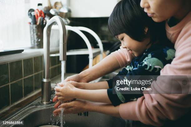 close up of an asian woman with her son washing their hands in the kitchen - content stock pictures, royalty-free photos & images