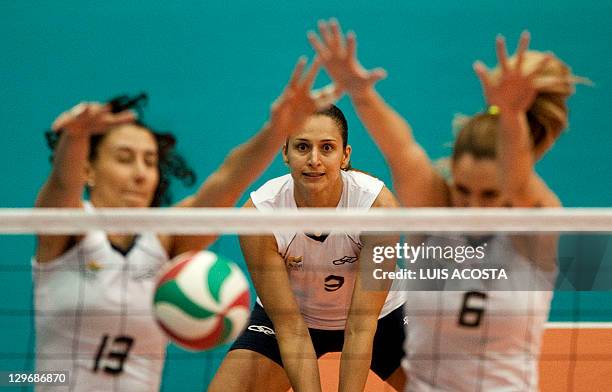 Brazil's Sheila Castro watches as teammates Sheila Castro and Thaisa Menezes block a shot from the Domican Republic during their semifinal volleyball...