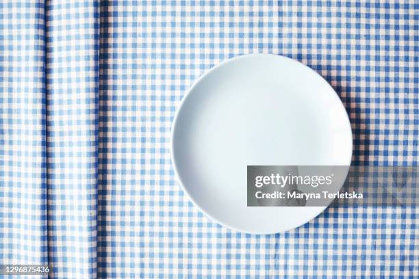 blue plate on a checkered blue-white fabric. - saucer fotografías e imágenes de stock