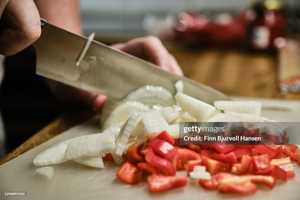 Hand cutting onions and red peppar with a knife