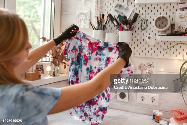 una joven haciendo ropa de tinte de corbata en casa. - teñido multicolor fotografías e imágenes de stock