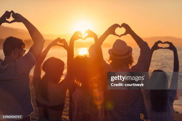 grupo de jóvenes haciendo señales de corazón de amor al atardecer. - an evening with heart fotografías e imágenes de stock