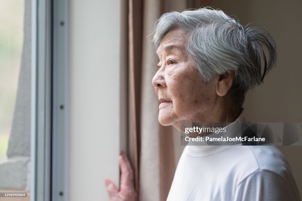 Serious Asian Senior Woman in 90s Looking Out of Window