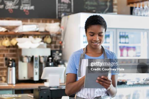 young adult woman holding digital tablet in café - waiter using digital tablet stock pictures, royalty-free photos & images
