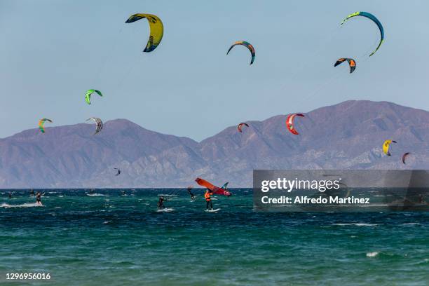 Kitewing and several kitesurfers ride through the splashing water of the Gulf of California during a day amid Covid-19 pandemic at Playa La Ventana...