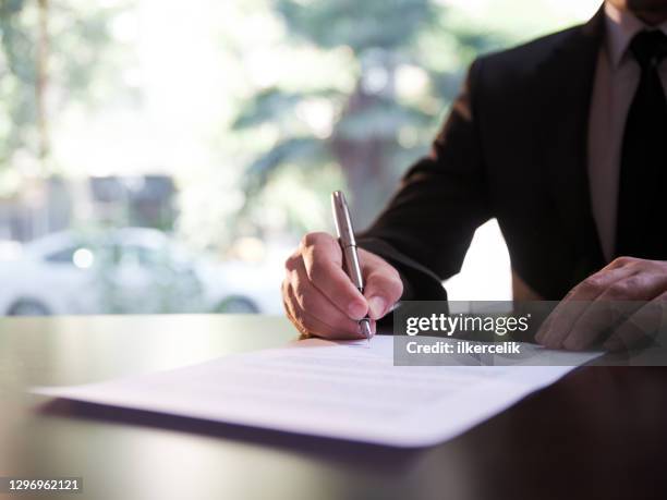 geschäftsmann, der einen vertrag oder rechtspapiere unterzeichnet - legal agreement stock-fotos und bilder