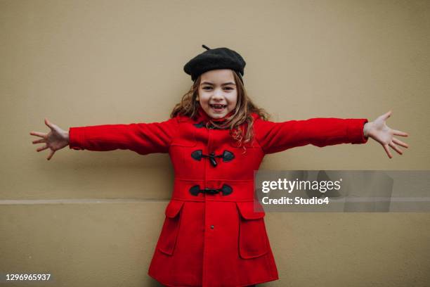 smiling girl spreading a hands to the camera - red coat stock pictures, royalty-free photos & images