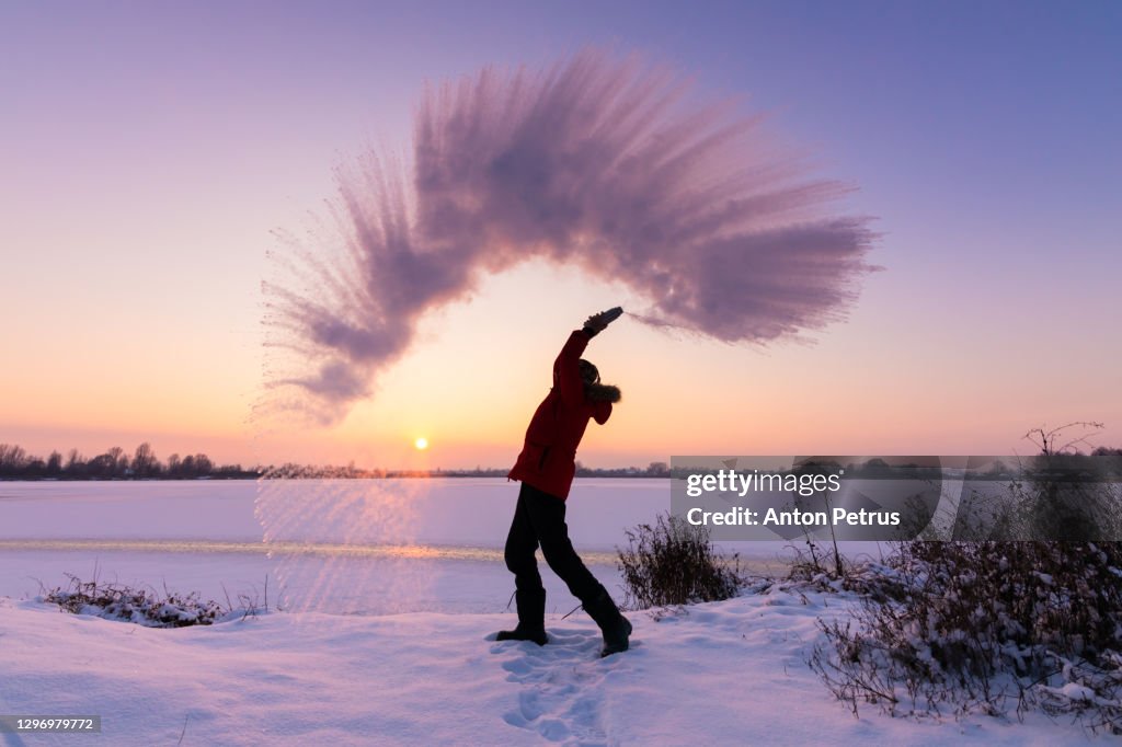 Man pours boiling water into the air in the bitter cold. Outdoor winter fun
