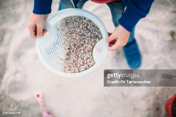 hands of a child playing with a sieve and sand - passoire photos et images de collection