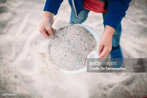 hands of a child playing with a sieve and sand - 1 kid 1 sandbox stock-fotos und bilder