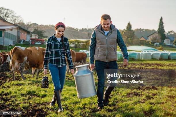 jeune femme et homme retenant la bidon de lait - rancher photos et images de collection