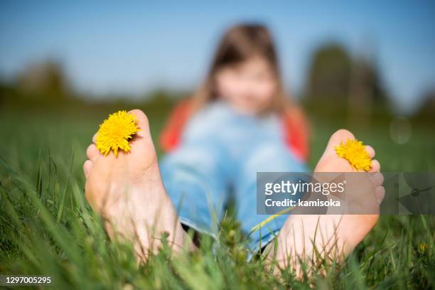 girl relaxing on the green grass with yellow dandelion between toes in sunny spring day - teen girls toes stock pictures, royalty-free photos & images